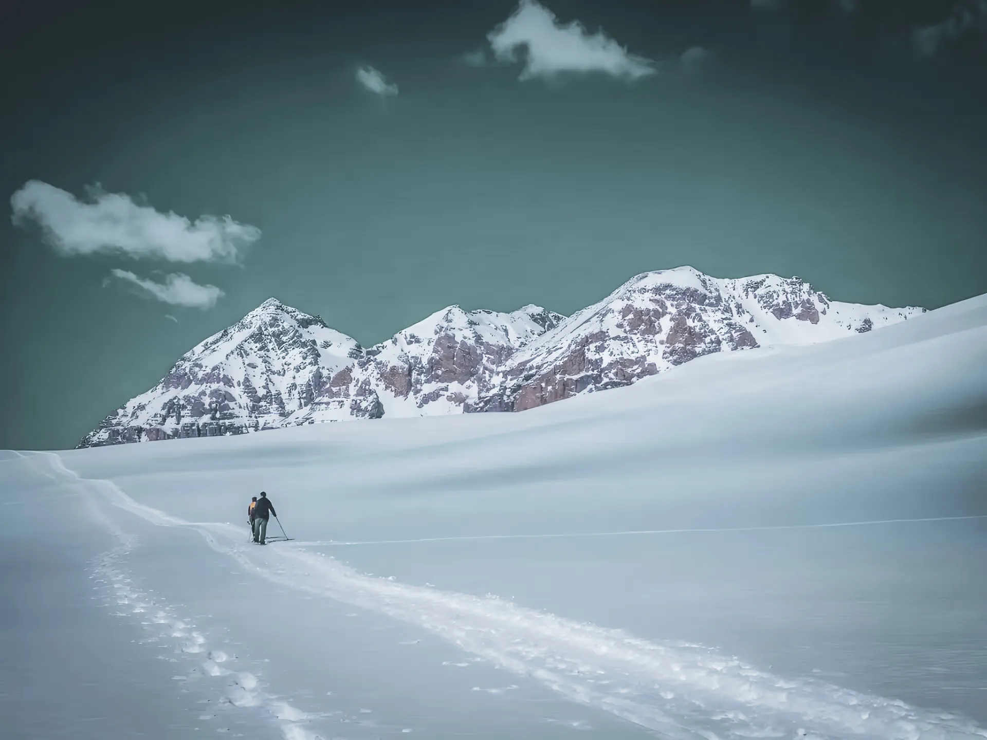 An adventurer on snowshoes on a vast snow-covered landscape, surrounded by majestic mountains.