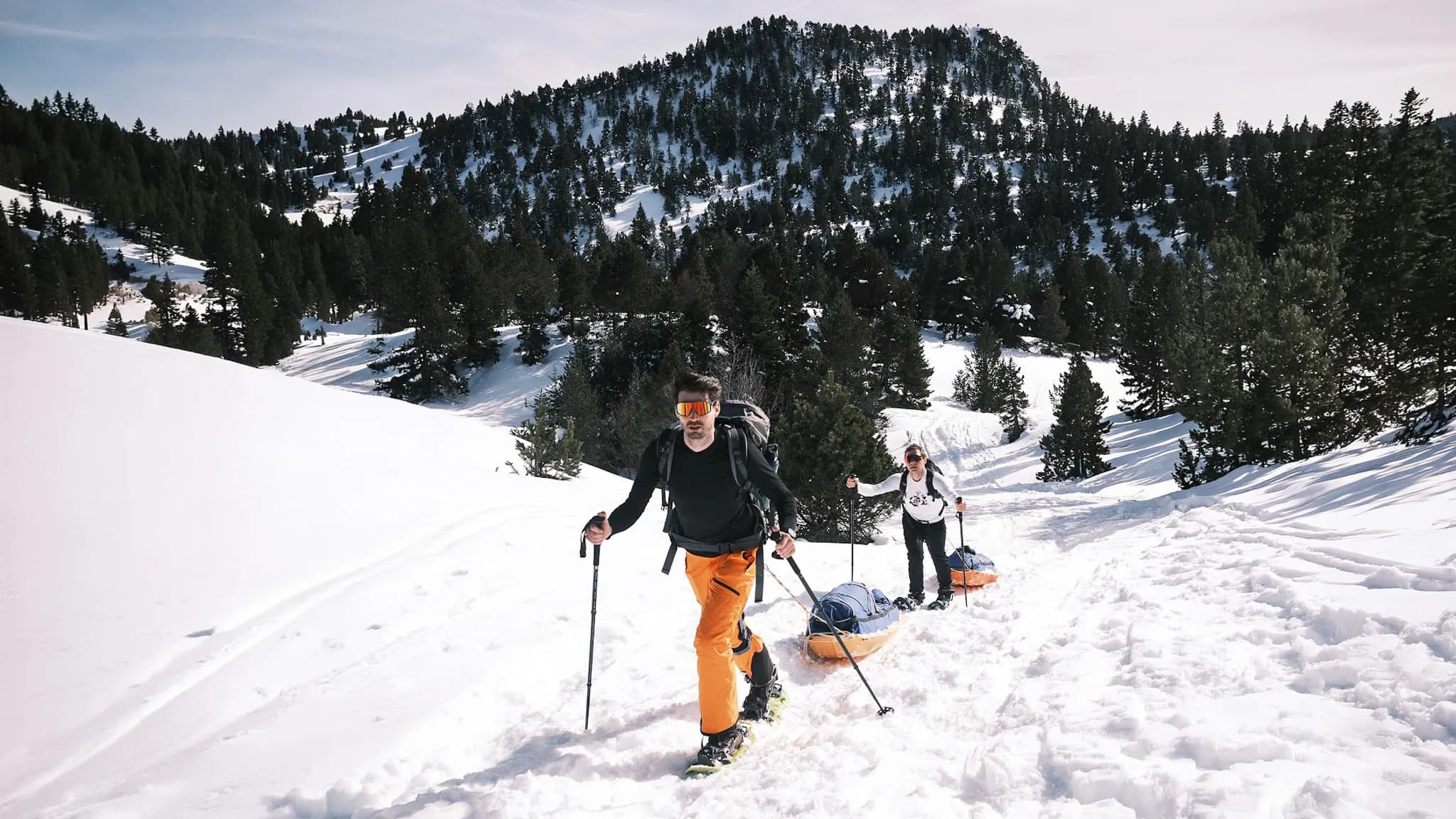 Deux randonneurs en raquettes progressent dans la neige, avec l'immense paysage du Vercors en arrière-plan.