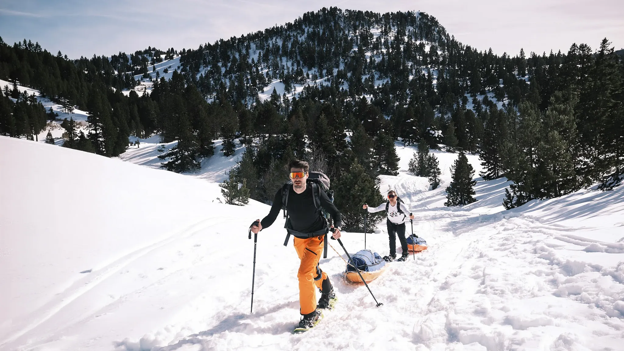 Deux randonneurs en raquettes progressent dans la neige, avec l'immense paysage du Vercors en arrière-plan.
