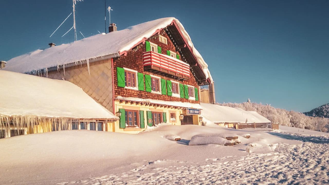 Charmante auberge enneigée sur la crête des Vosges, invitant à l'évasion en raquettes.