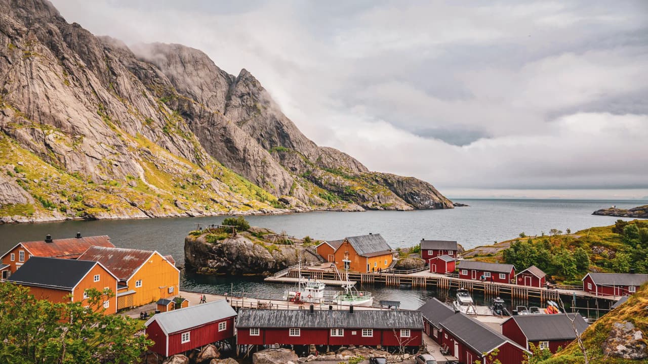 A picturesque village in Lofoten, overlooked by majestic mountains and a calm fjord.