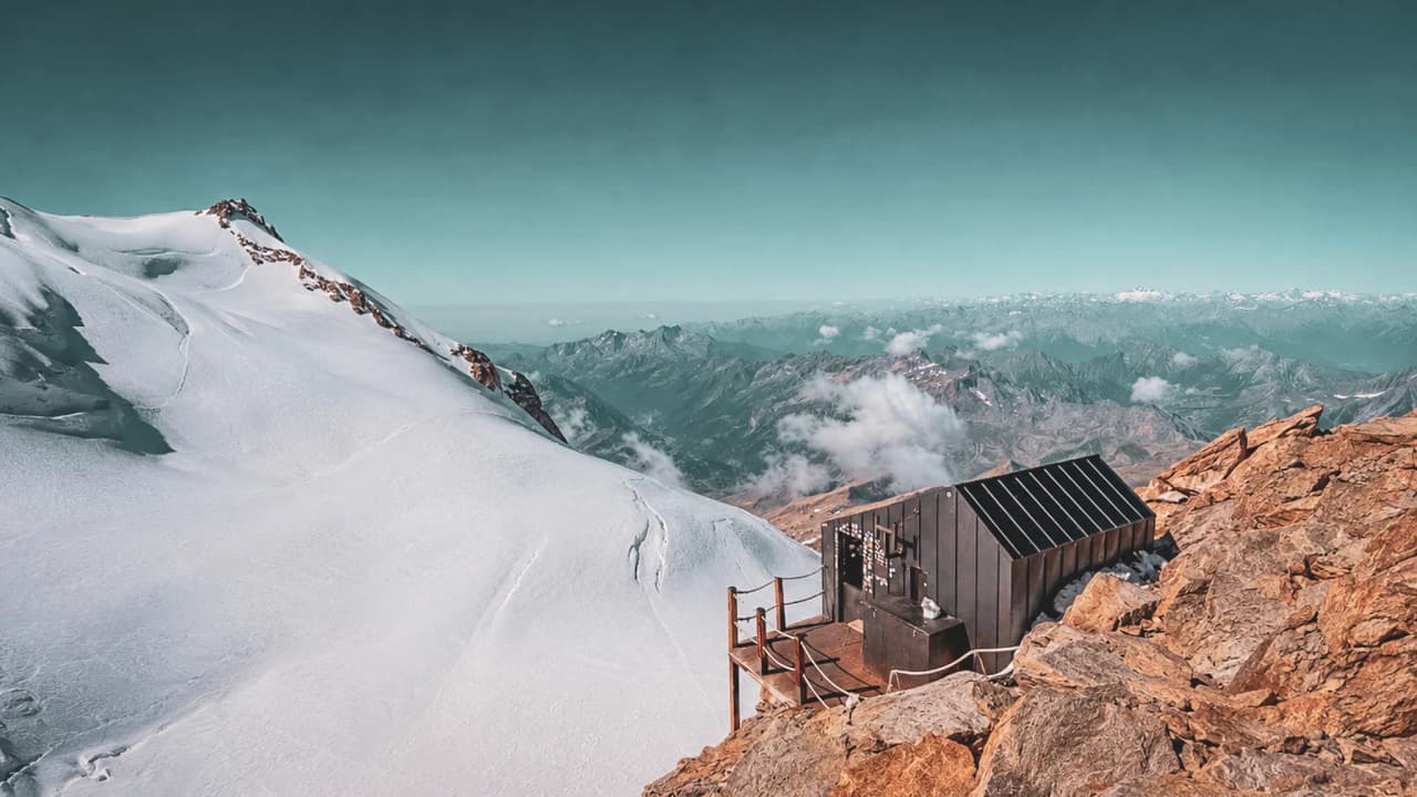 A modern mountain hut, surrounded by majestic Alpine landscapes and snow-capped peaks.
