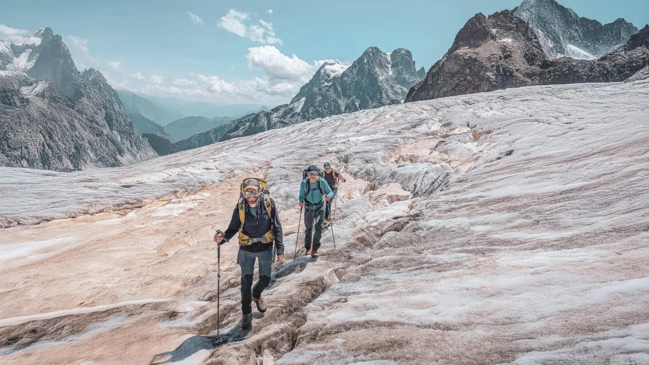 Voyage en montagne : des alpinistes gravissent un glacier, entourés de paysages grandioses.
