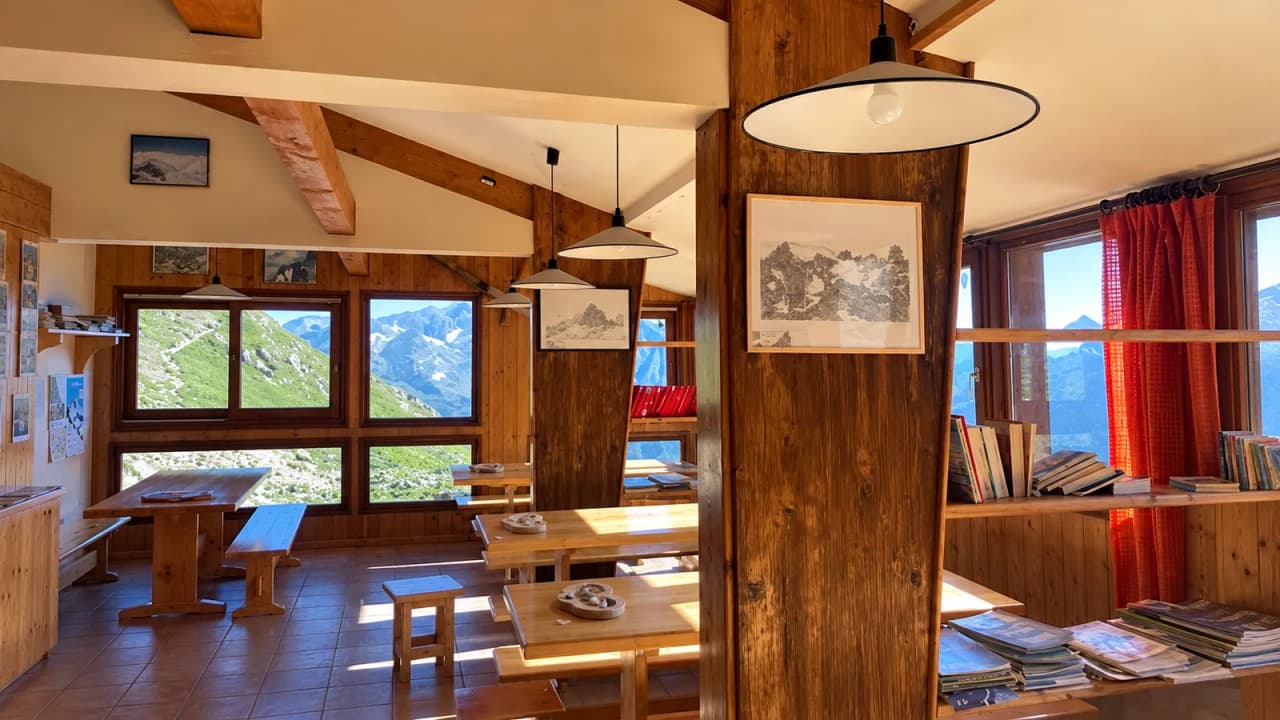 A light-filled interior in a mountain hut, with panoramic views of the peaks and high-altitude lakes.