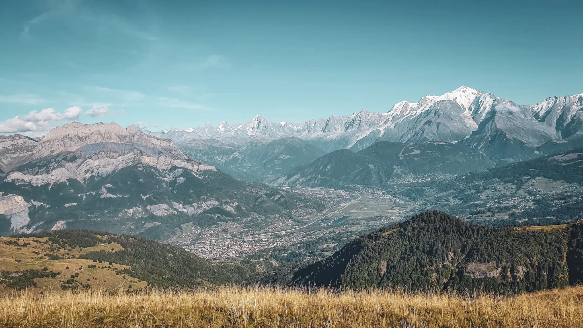 Panorama époustouflant des montagnes des Aravis, vallées verdoyantes et ciel bleu éclatant.