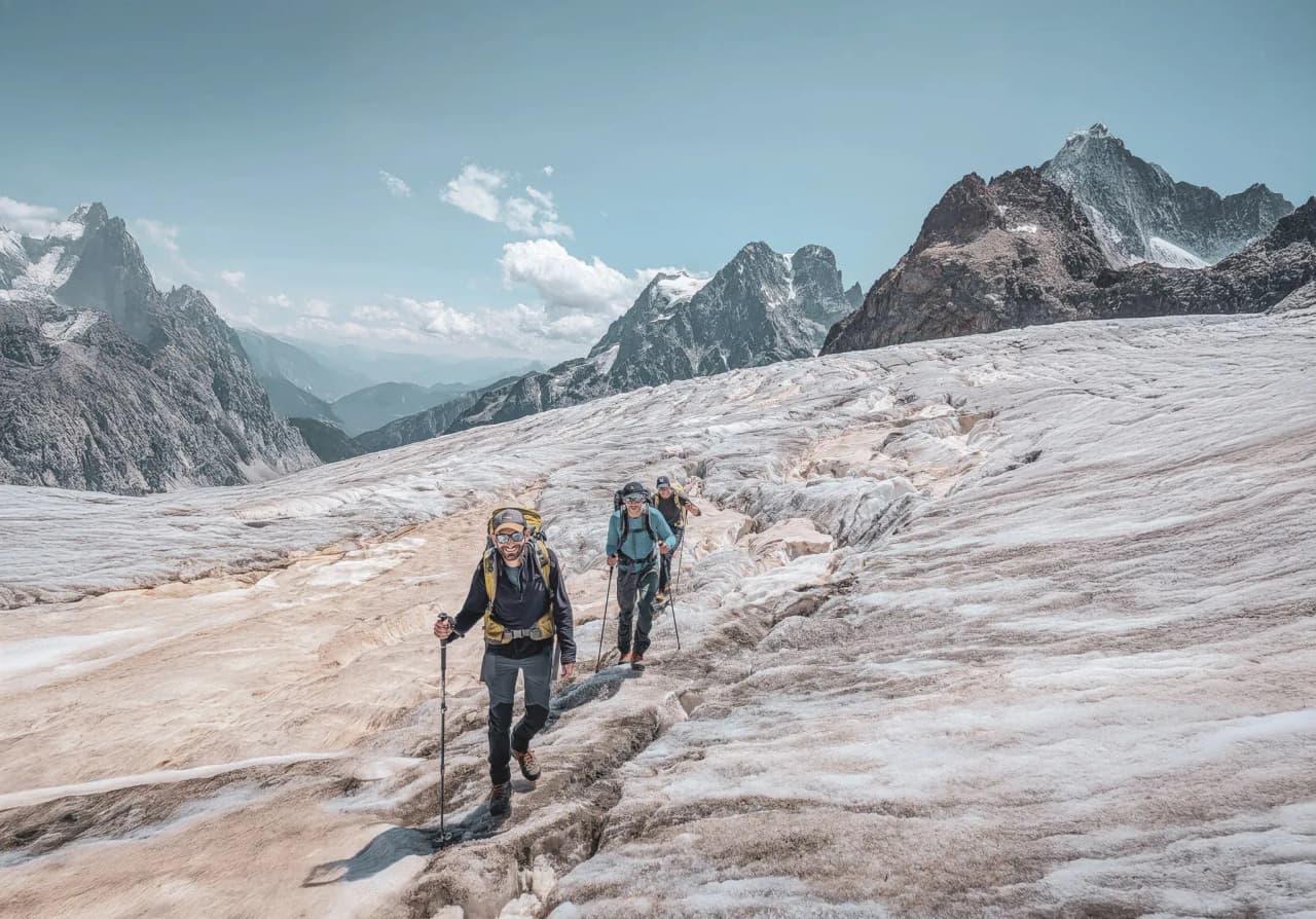Group of climbers on a glacier in the Écrins, with majestic peaks in the background.