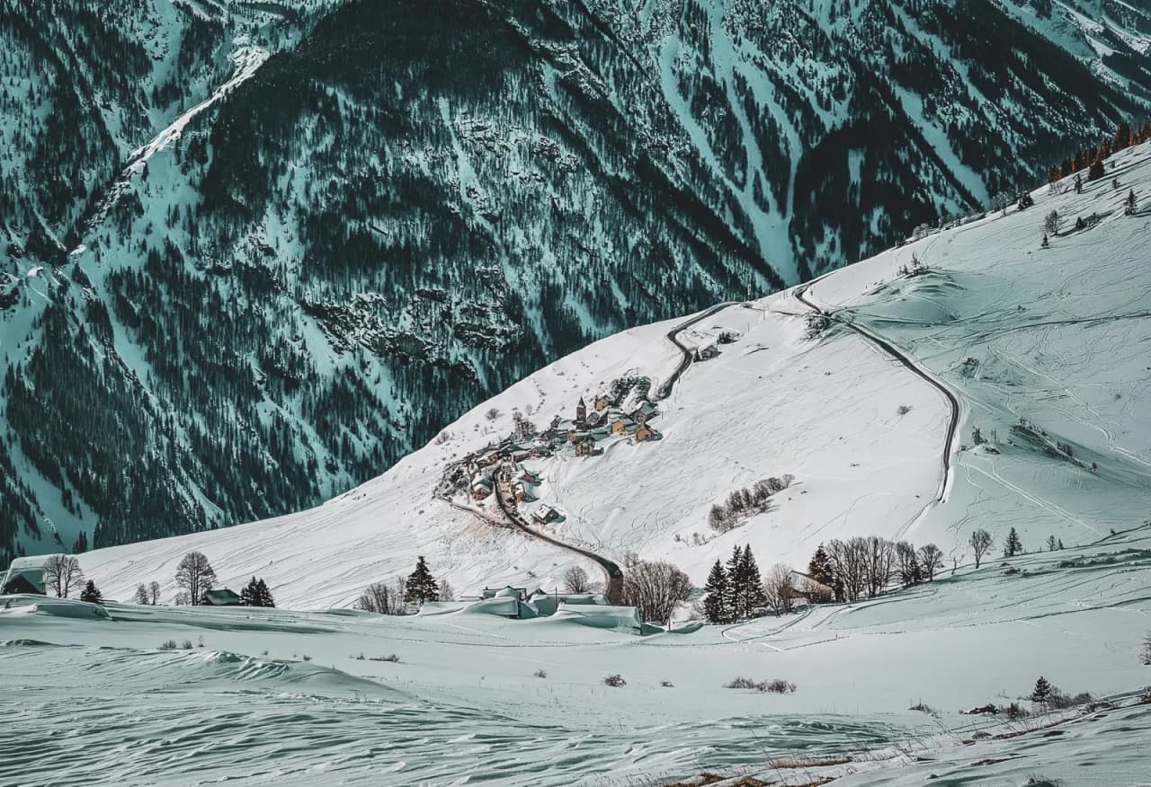 Besneeuwd Alpenlandschap, pittoresk dorpje omringd door majestueuze bergen en dennenbomen.