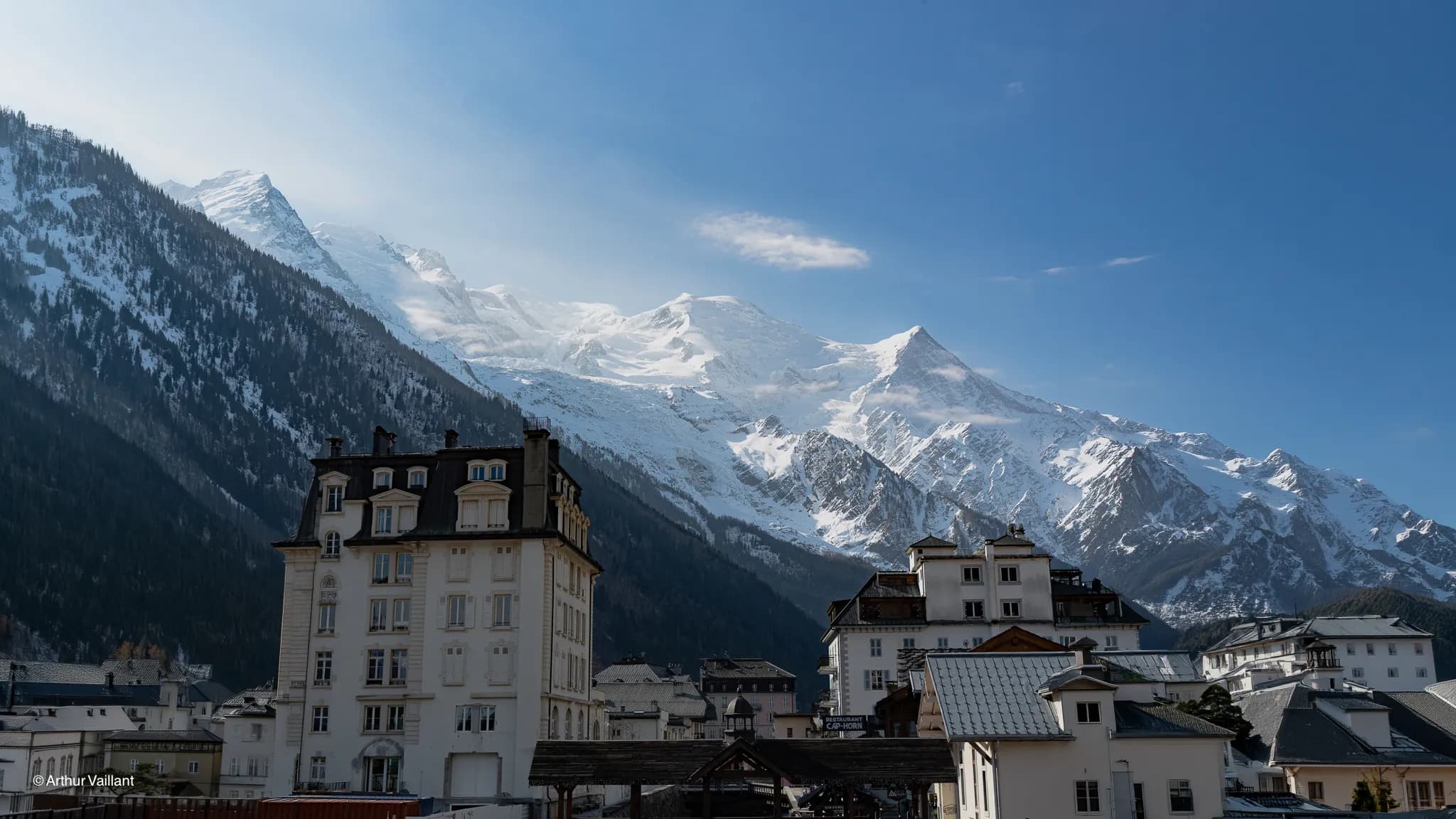 A panoramic view of the majestic snow-capped mountains of Chamonix, beneath a brilliant blue sky.
