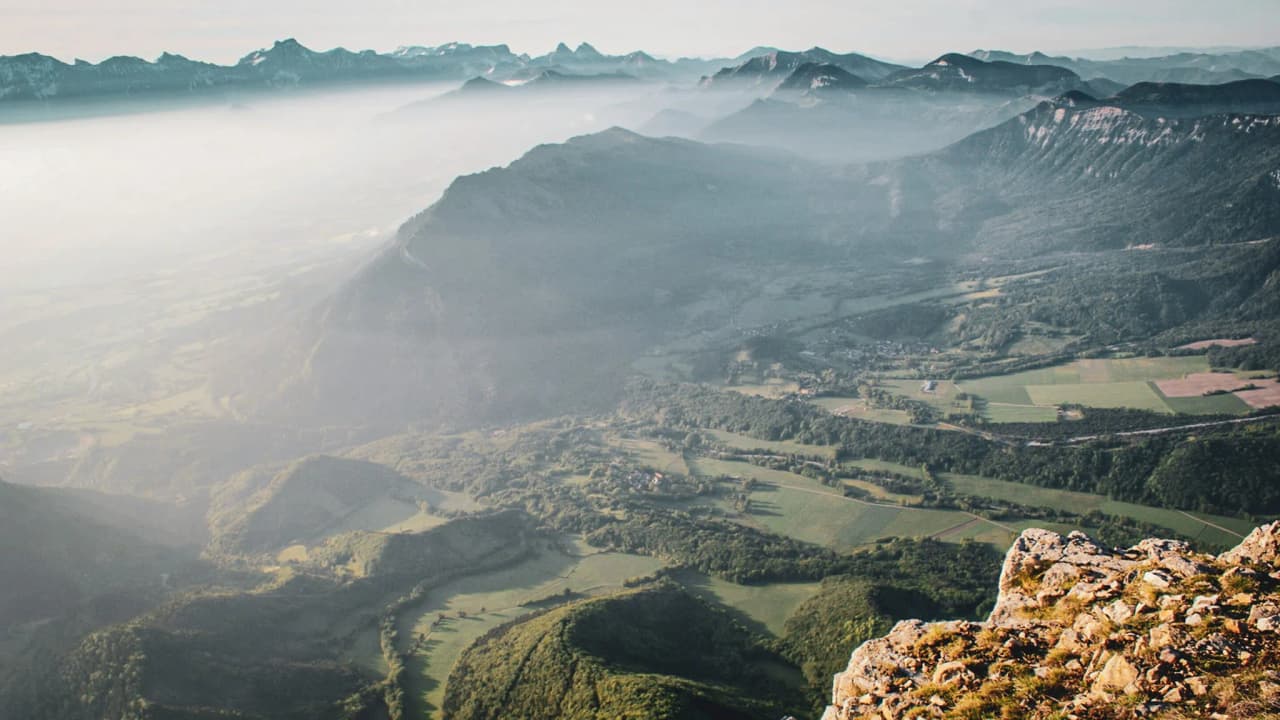 Spectaculair uitzicht vanaf de Mont Aiguille, met mistige bergen en groene valleien.