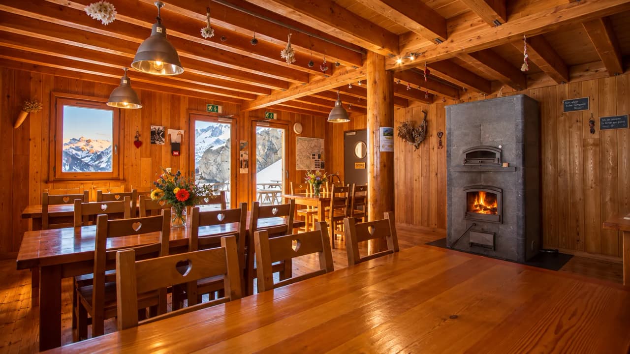 The cosy interior of a wooden inn, with views of the snow-capped mountains. Warm and welcoming.