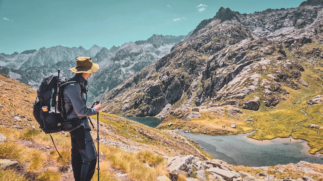 Een wandelaar die geniet van een majestueus uitzicht in de Hautes-Pyrénées, tussen meren en bergen.
