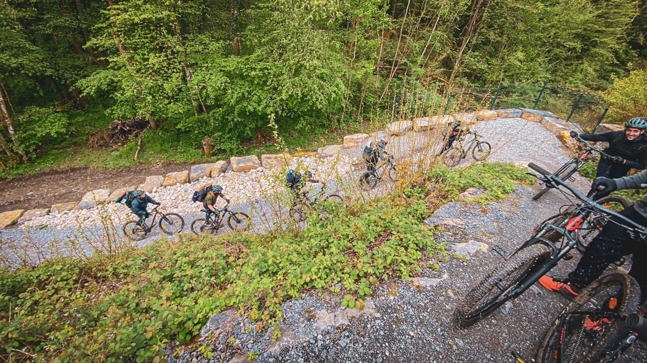 Cyclists climb a path surrounded by greenery, ready for a wilderness adventure.