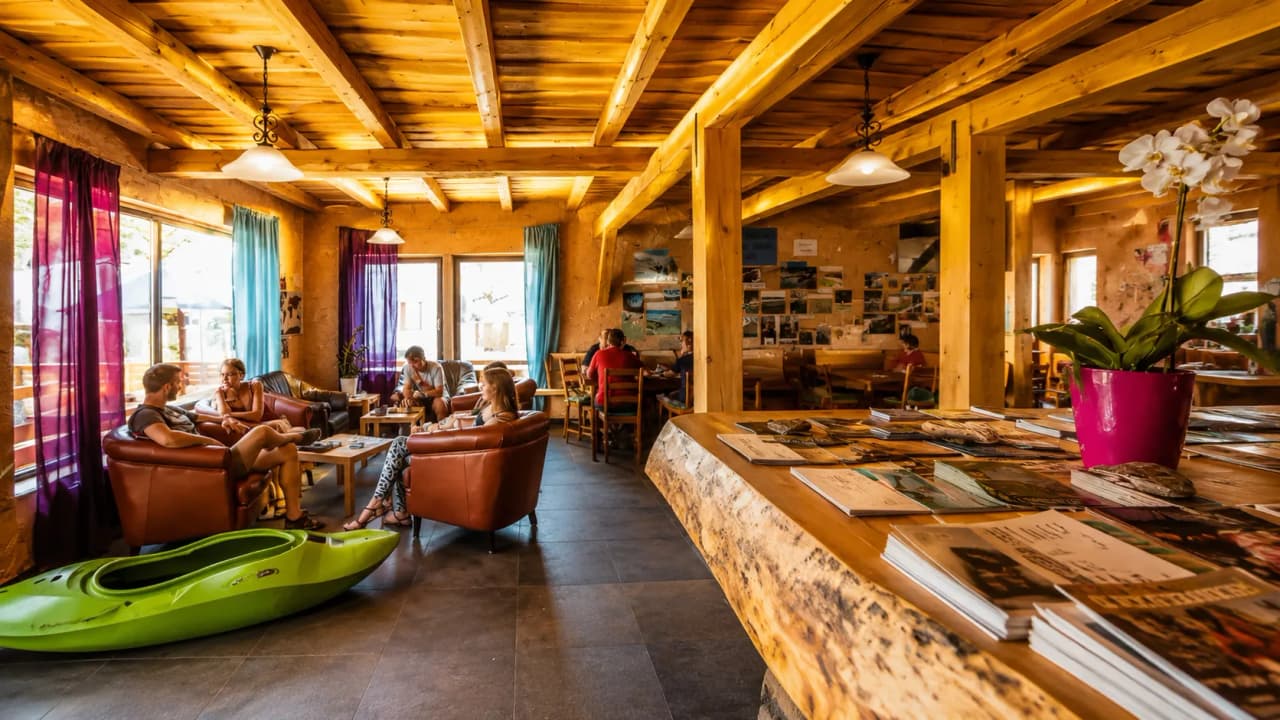A welcoming space with sofas, wooden décor and a green packraft, ideal for adventure.
