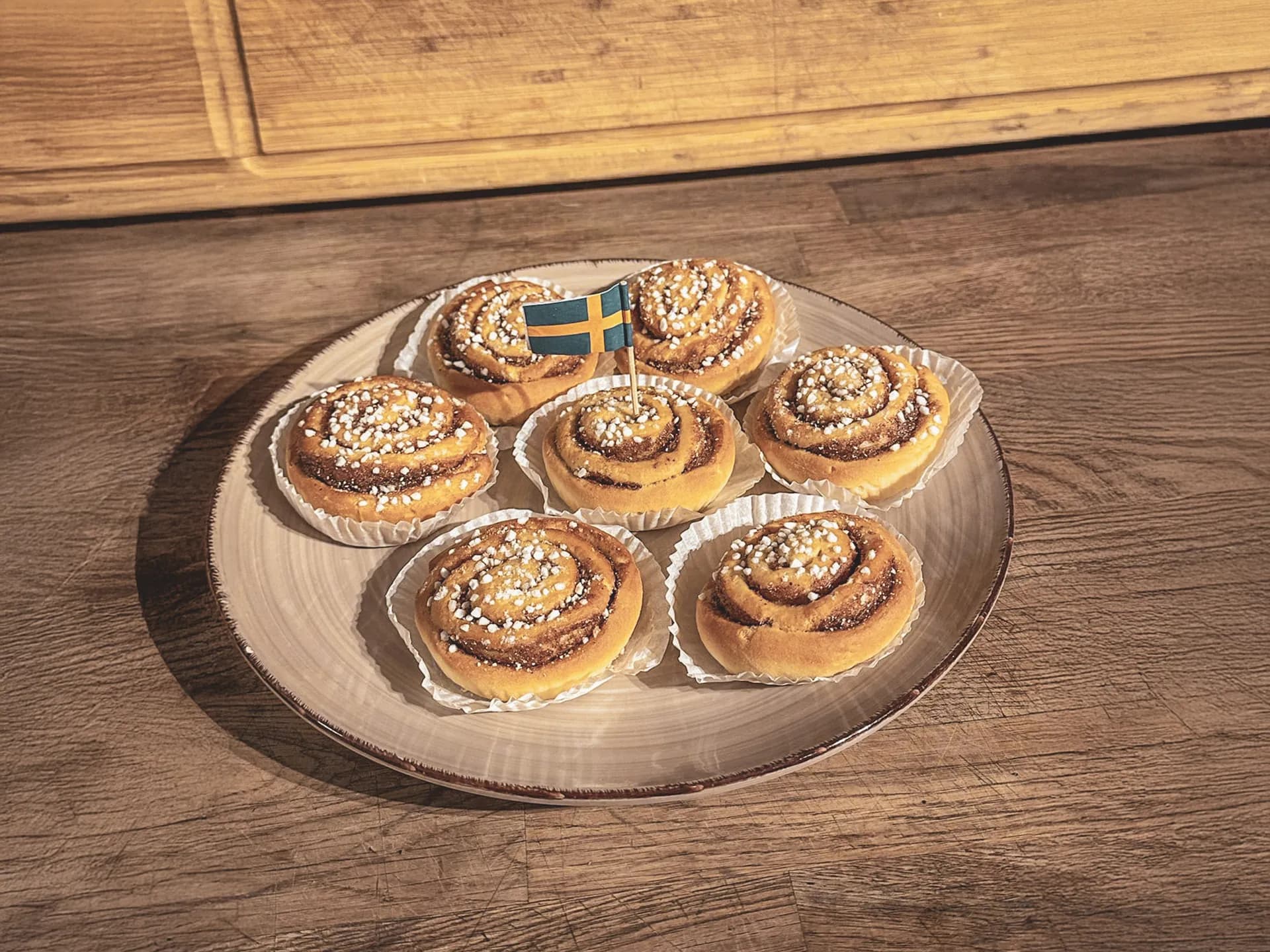 Sept délicieuses cinnamon rolls sur une assiette, décorées de sucre, évoquant la douceur de la Laponie.