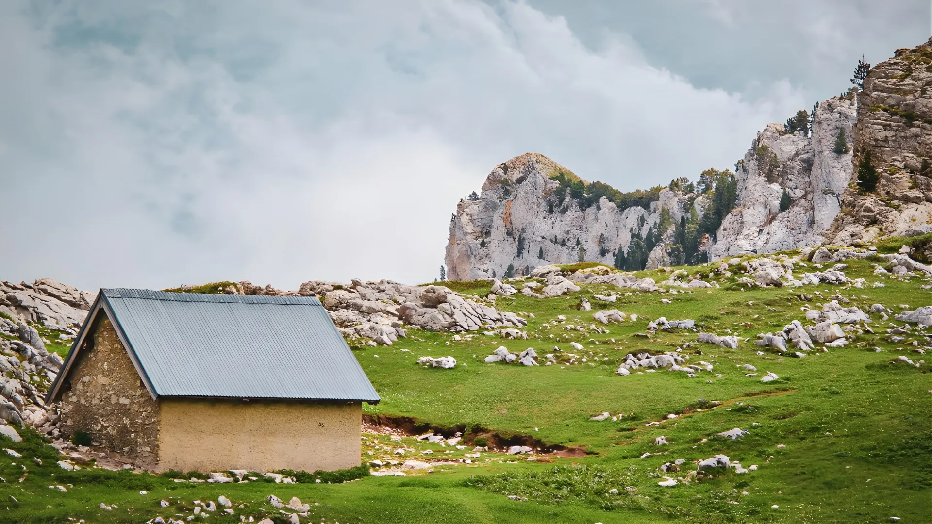Une charmante cabane en pleine nature, entourée de rochers et de prairies verdoyantes.