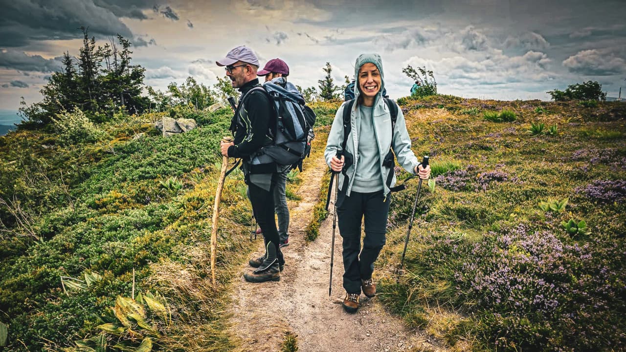 Three smiling hikers on a green trail in the Vosges, surrounded by nature and wonder.