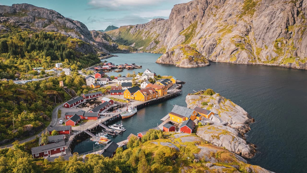 A charming, colourful village on the edge of a fjord, surrounded by lush green mountains. Escape to Norway!