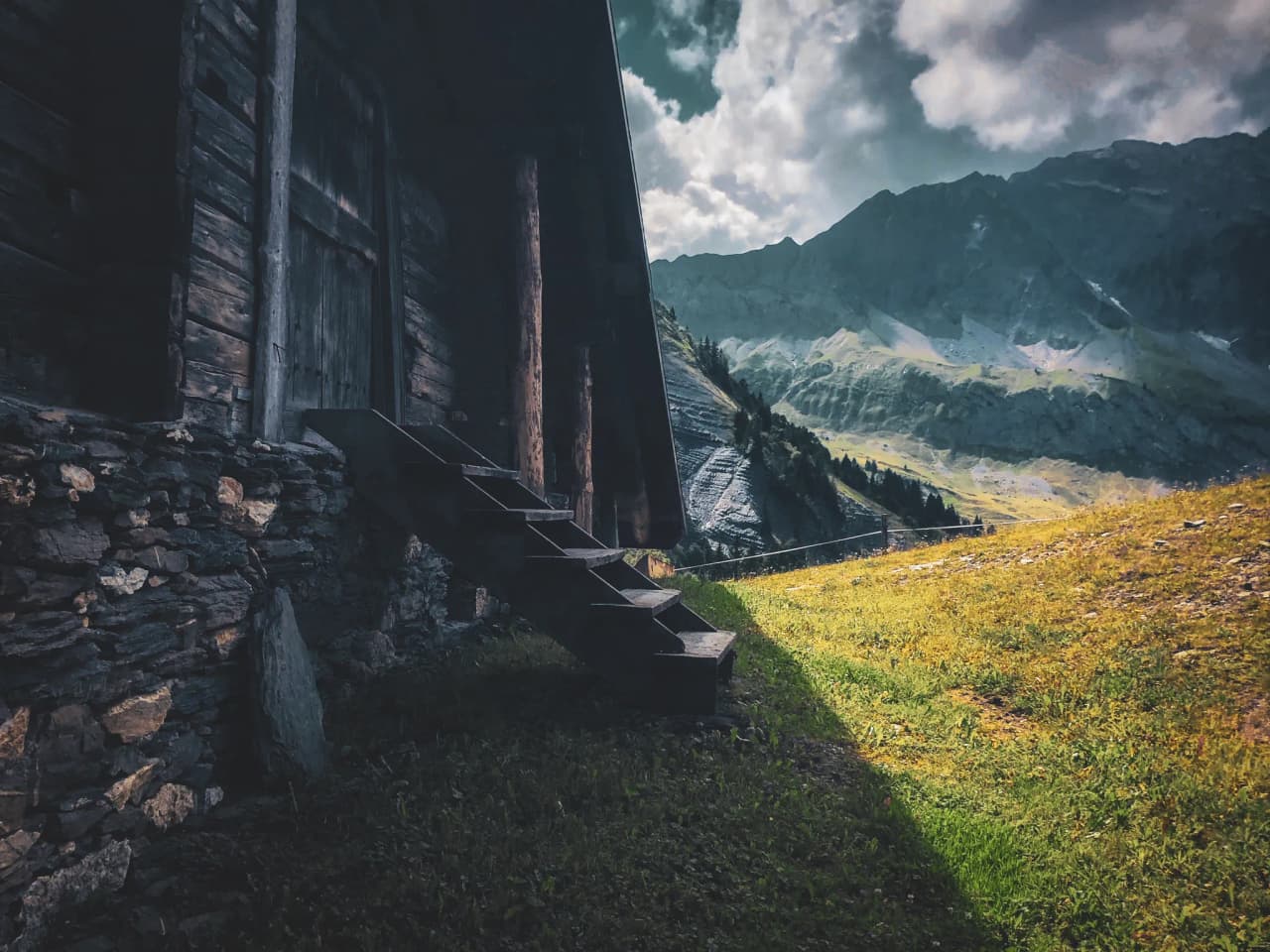 Wooden stairs leading to a cabin, with majestic mountains in the background.