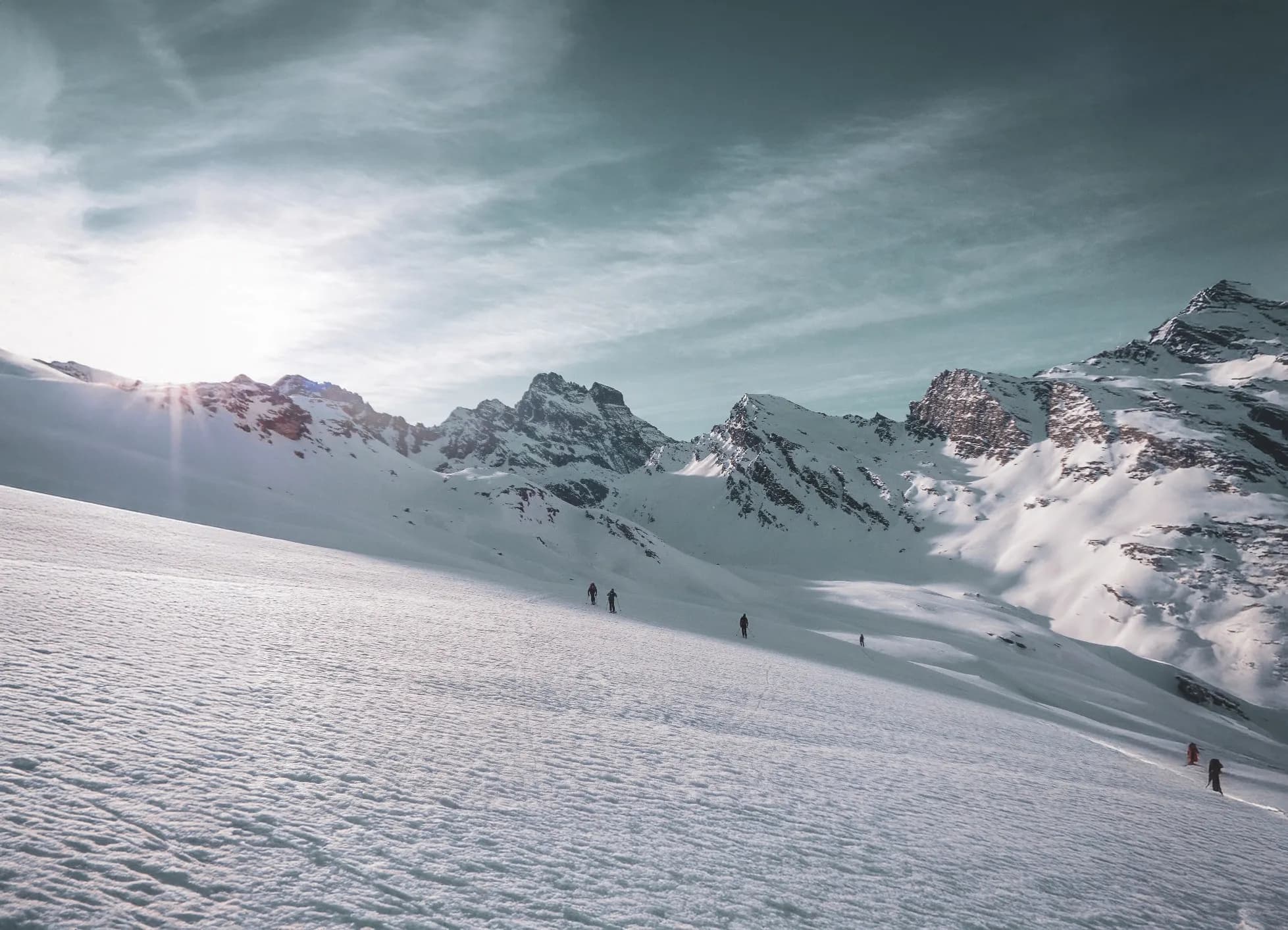 Panorama alpin au soleil, aventuriers skiant sur neige immaculée, paysages majestueux du Mont Viso.