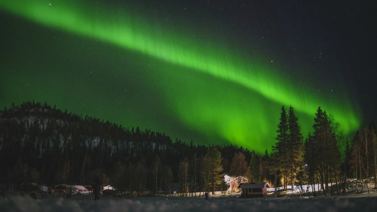 Spectacular Northern Lights against a starry sky, set against the backdrop of a peaceful, snow-covered Swedish landscape.