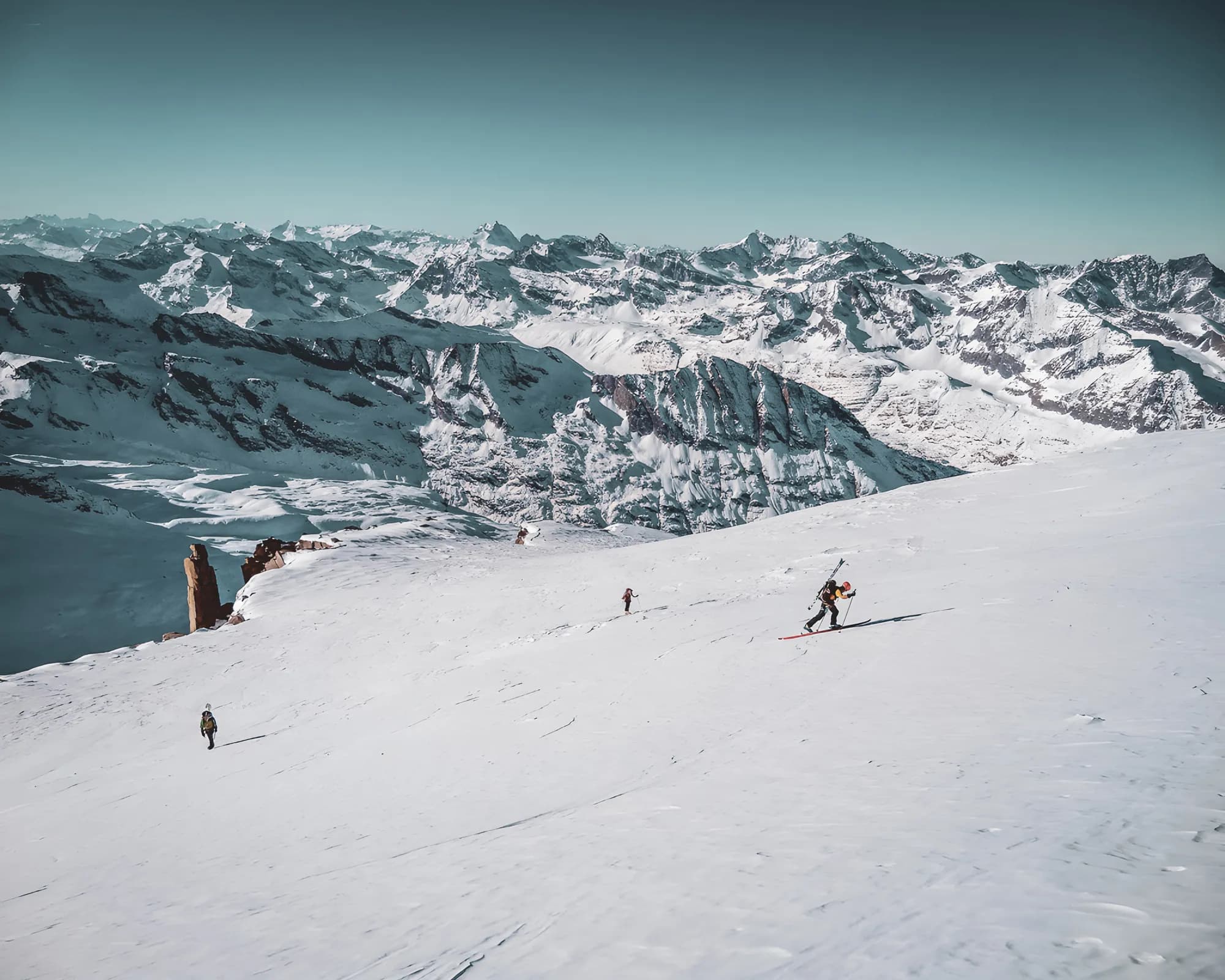 Un panorama alpin époustouflant avec des skieurs sur une neige immaculée, entourés de montagnes majestueuses.