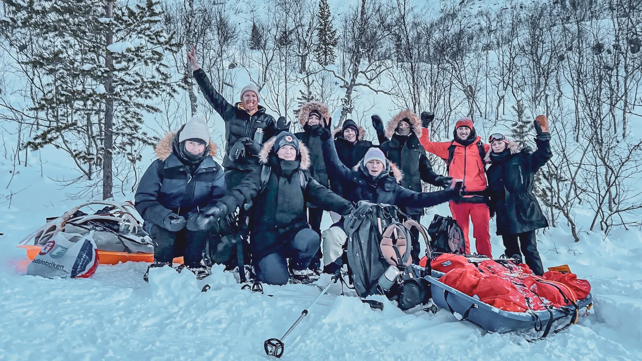 Een lachende groep in de sneeuw, klaar voor een avontuur in Zweeds Lapland.