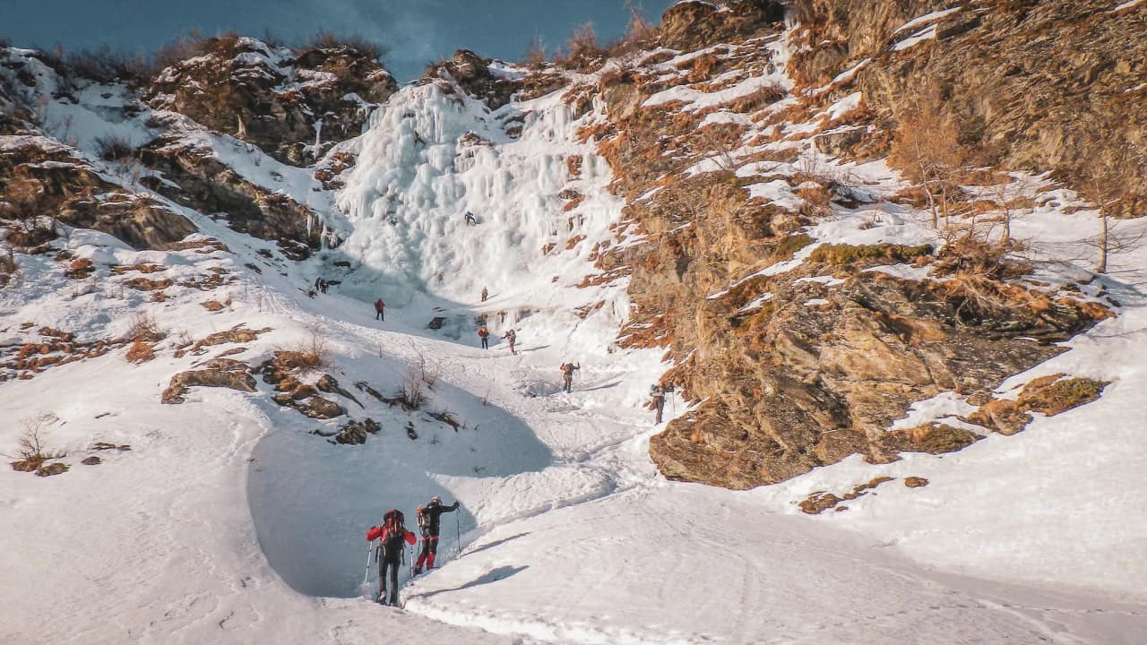 A group of adventurers on immaculate snow, facing a sparkling waterfall of ice.
