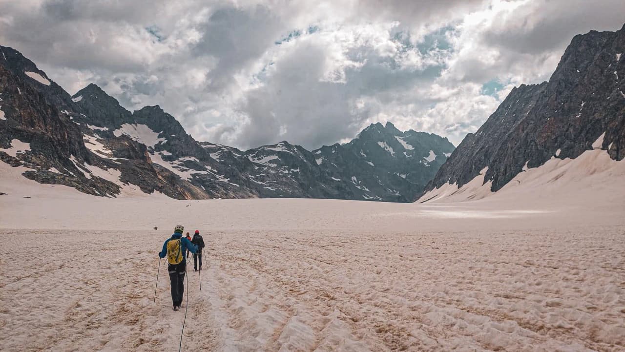 Groupe d'alpinistes progressant sur un glacier majestueux, entouré de montagnes. Aventure garantie !
