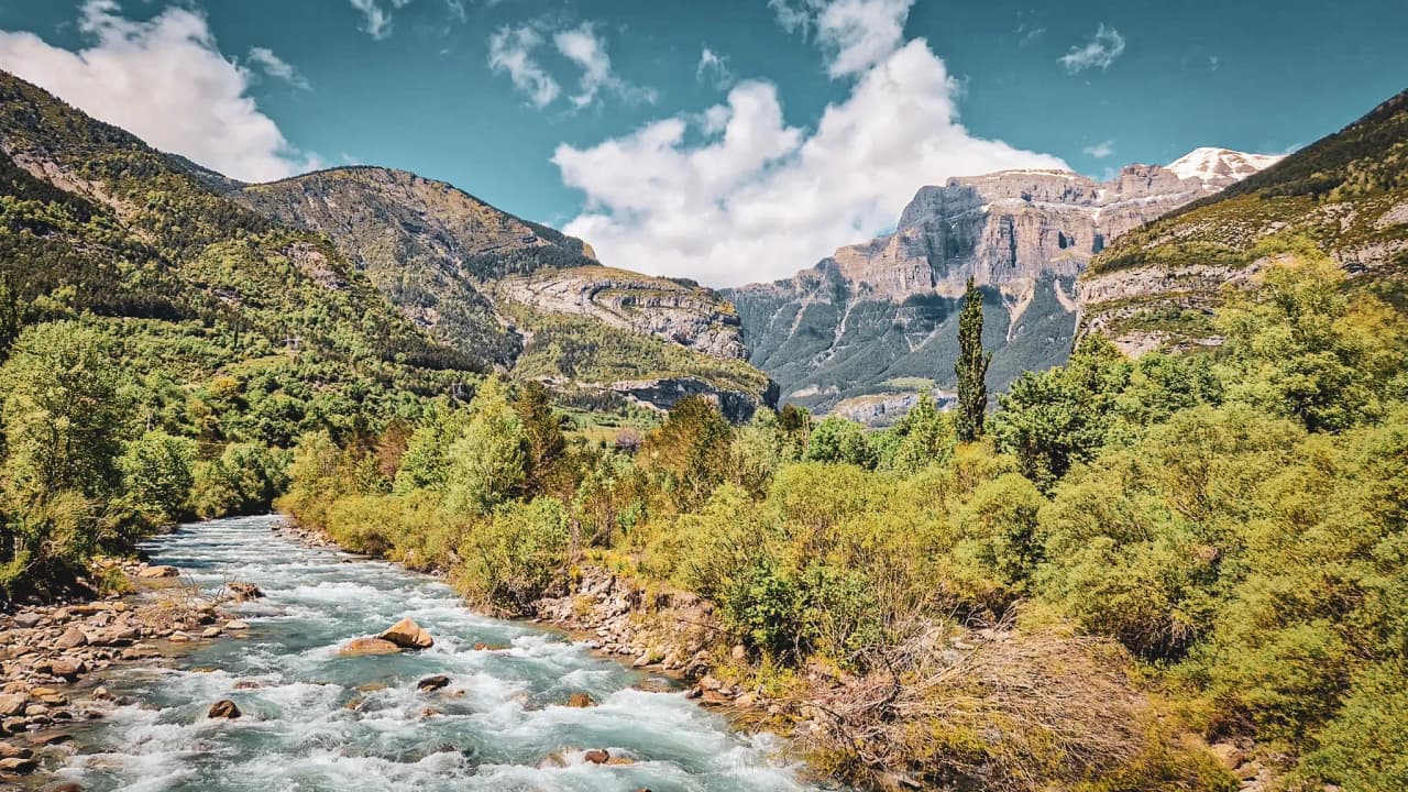 Een kristalheldere rivier omringd door majestueuze groene bergen, een uitnodiging voor avontuur in de Pyreneeën.