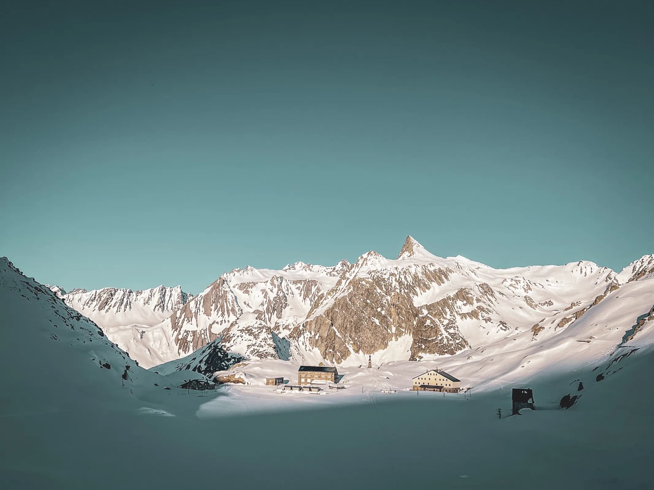 Magnifique paysage alpin au col du Grand-Saint-Bernard, entre sommets enneigés et refuges chaleureux.