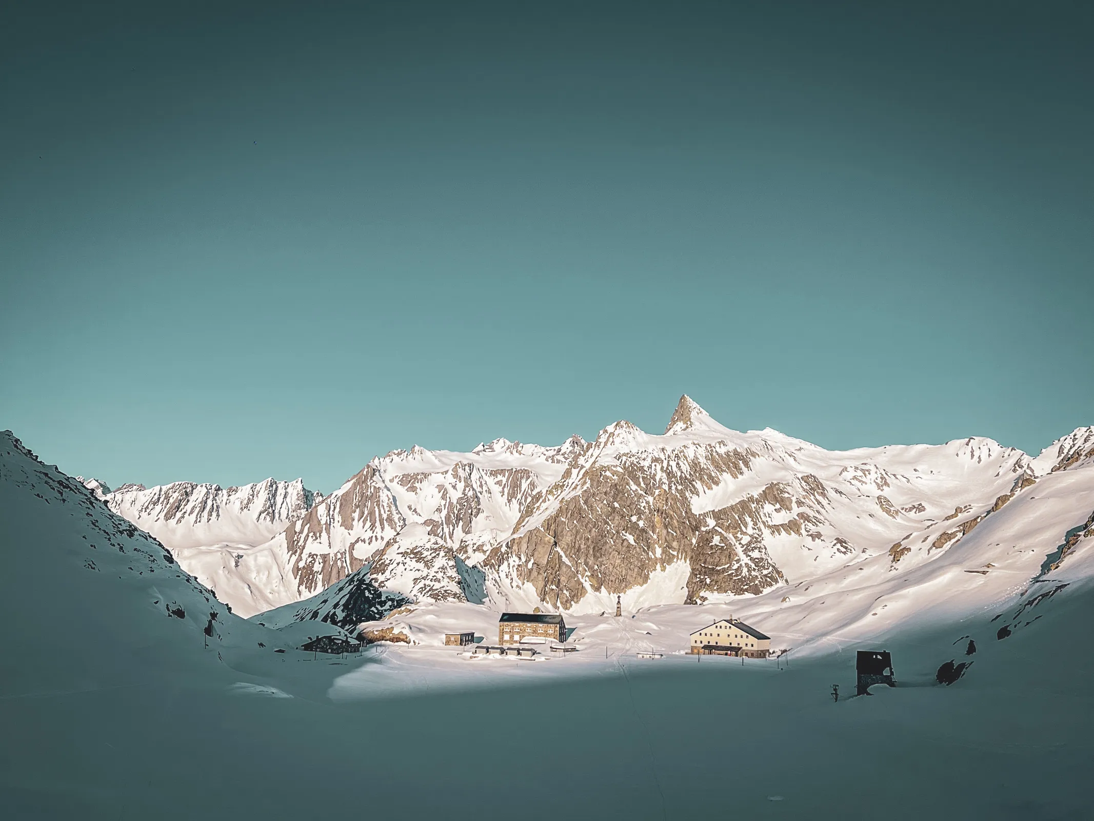 Magnifique paysage alpin au col du Grand-Saint-Bernard, entre sommets enneigés et refuges chaleureux.