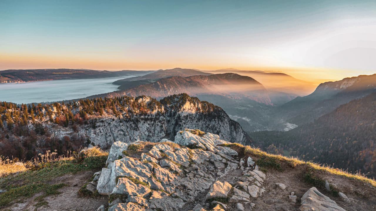 Vast panorama of the Jura mountains at sunrise, between mist and serenity.