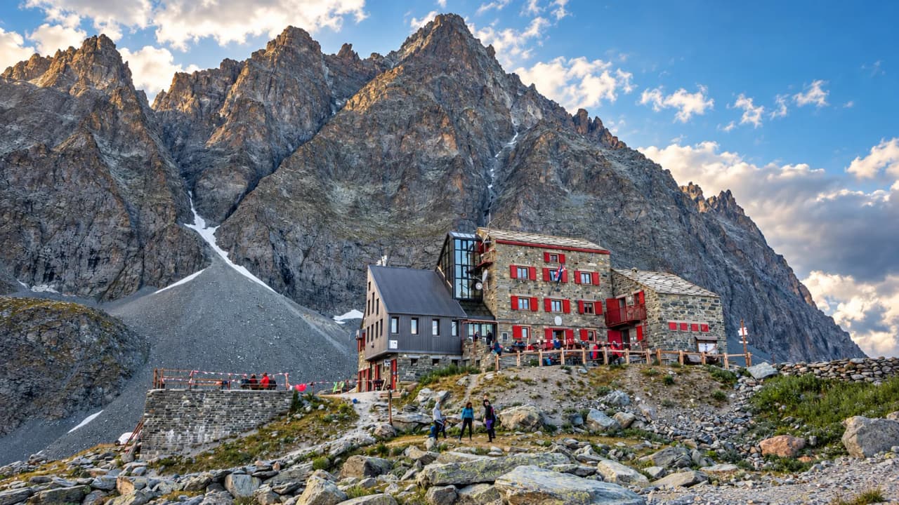 A picturesque mountain hut at the foot of the majestic mountains, an invitation to an alpine adventure.