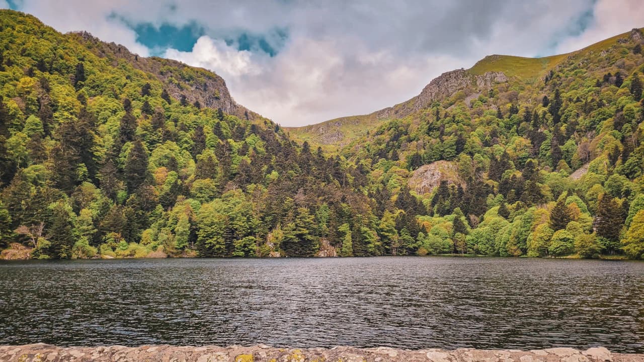 Lac paisible encerclé de montagnes verdoyantes, idéal pour l'évasion en pleine nature.