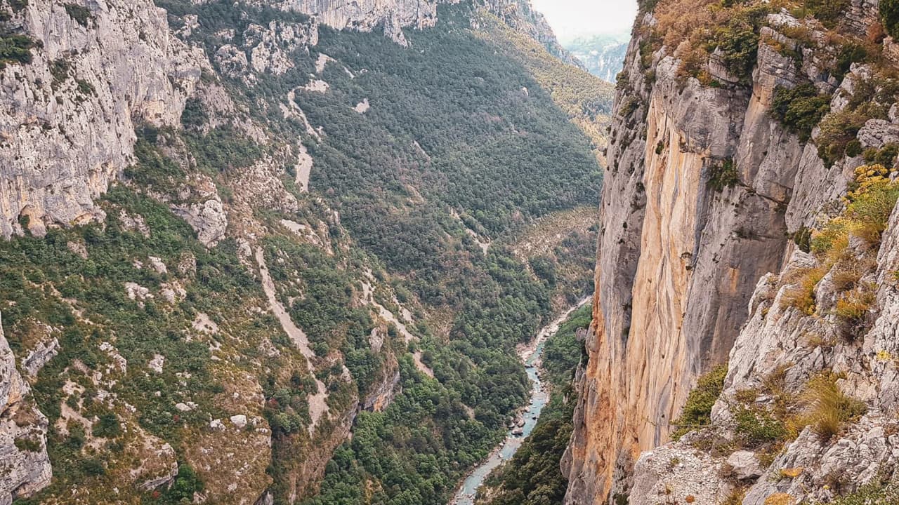 De majestueuze rotswanden van de Gorges du Verdon torenen hoog boven een turkooizen rivier uit die zich beneden kronkelend een weg baant.