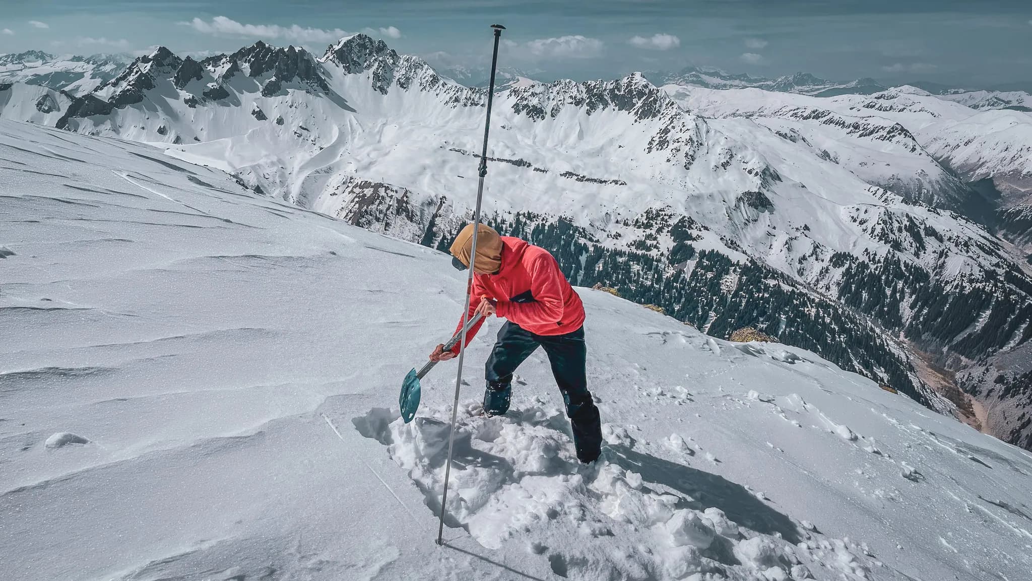 People digging in the snow, majestic mountains in the background, incredible scenery.