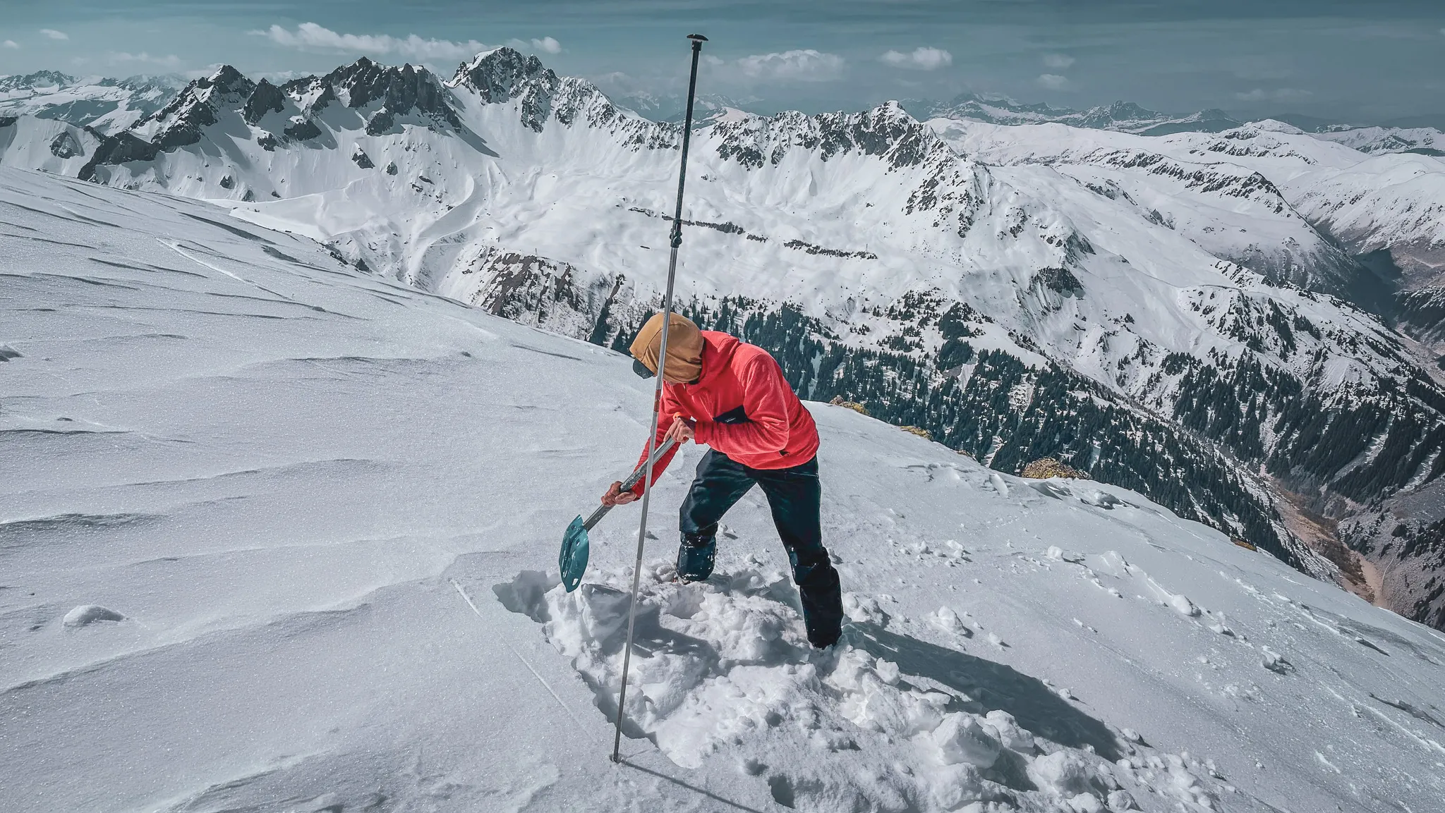 People digging in the snow, majestic mountains in the background, incredible scenery.