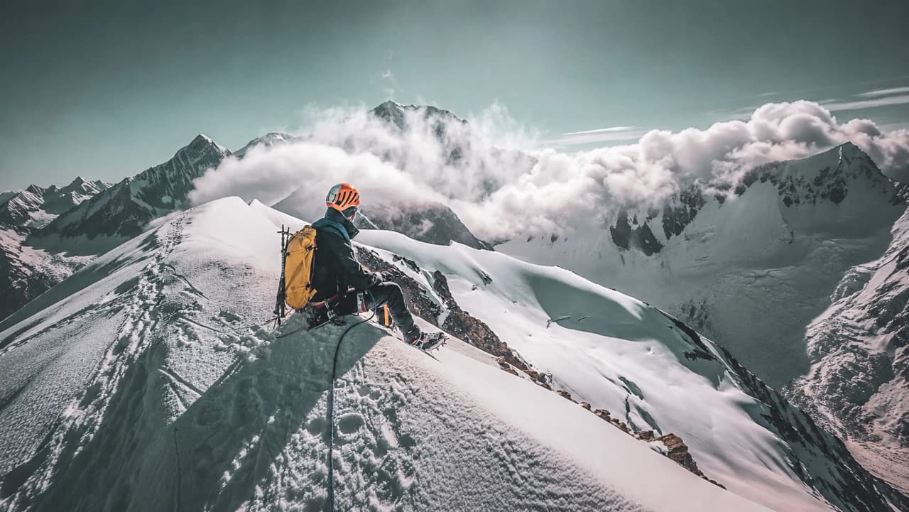 Bergbeklimmer kijkt uit over een adembenemend panorama van de Dômes de Miage en de Mont Blanc.