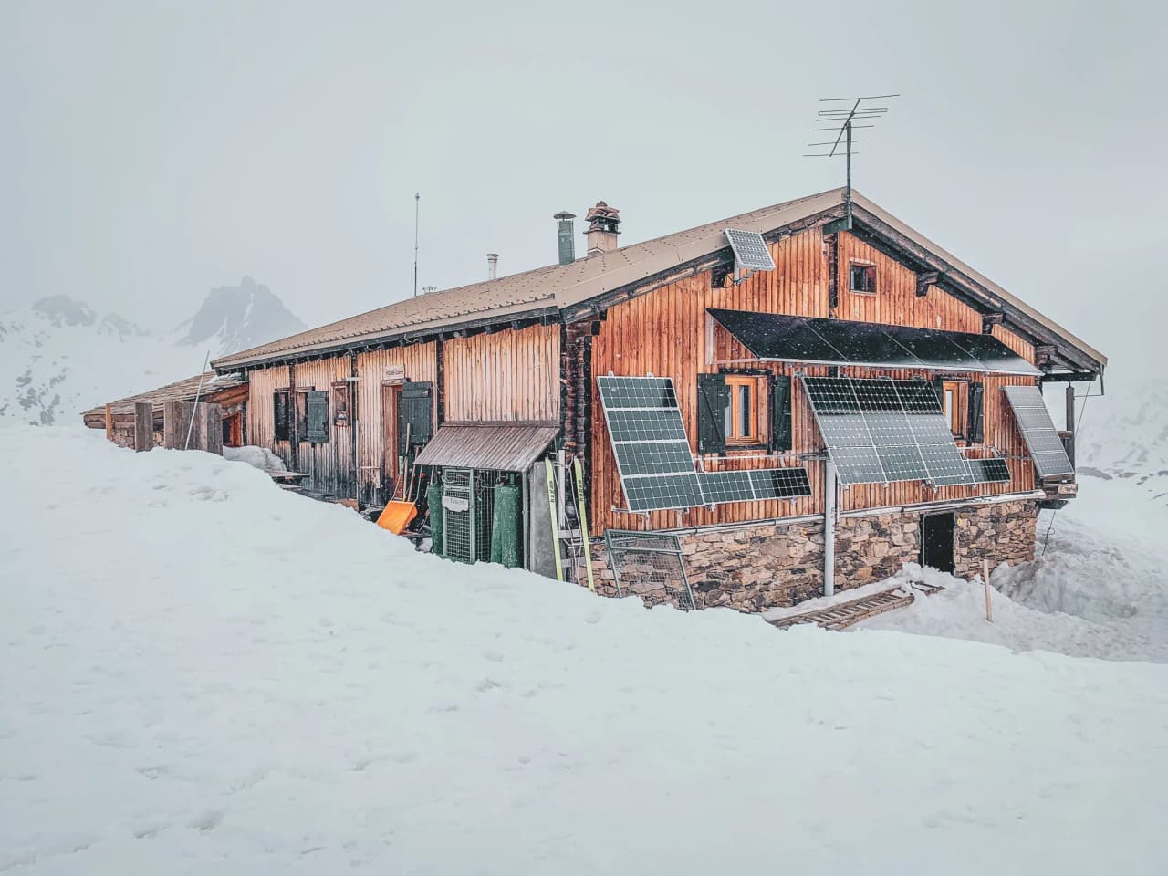 Een houten berghut verscholen in de sneeuw, omringd door majestueuze bergen. De ideale alpine vakantiebestemming.