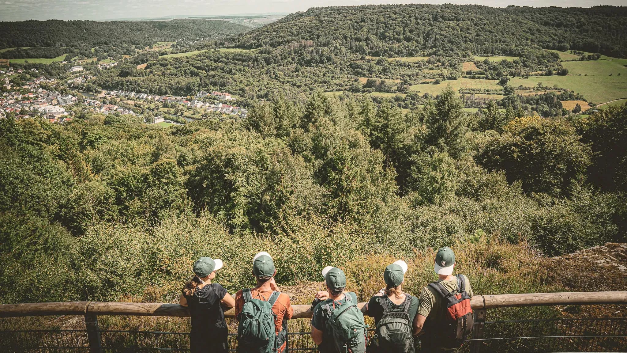 Groupe de randonneurs admirant un paysage verdoyant de la Petite Suisse luxembourgeoise.