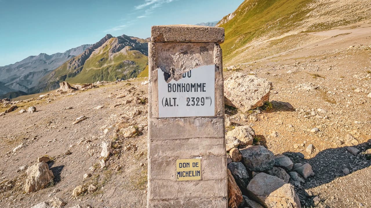 Col du Bonhomme: a stone sign with lush green mountains in the background, inviting you to embark on an adventure.
