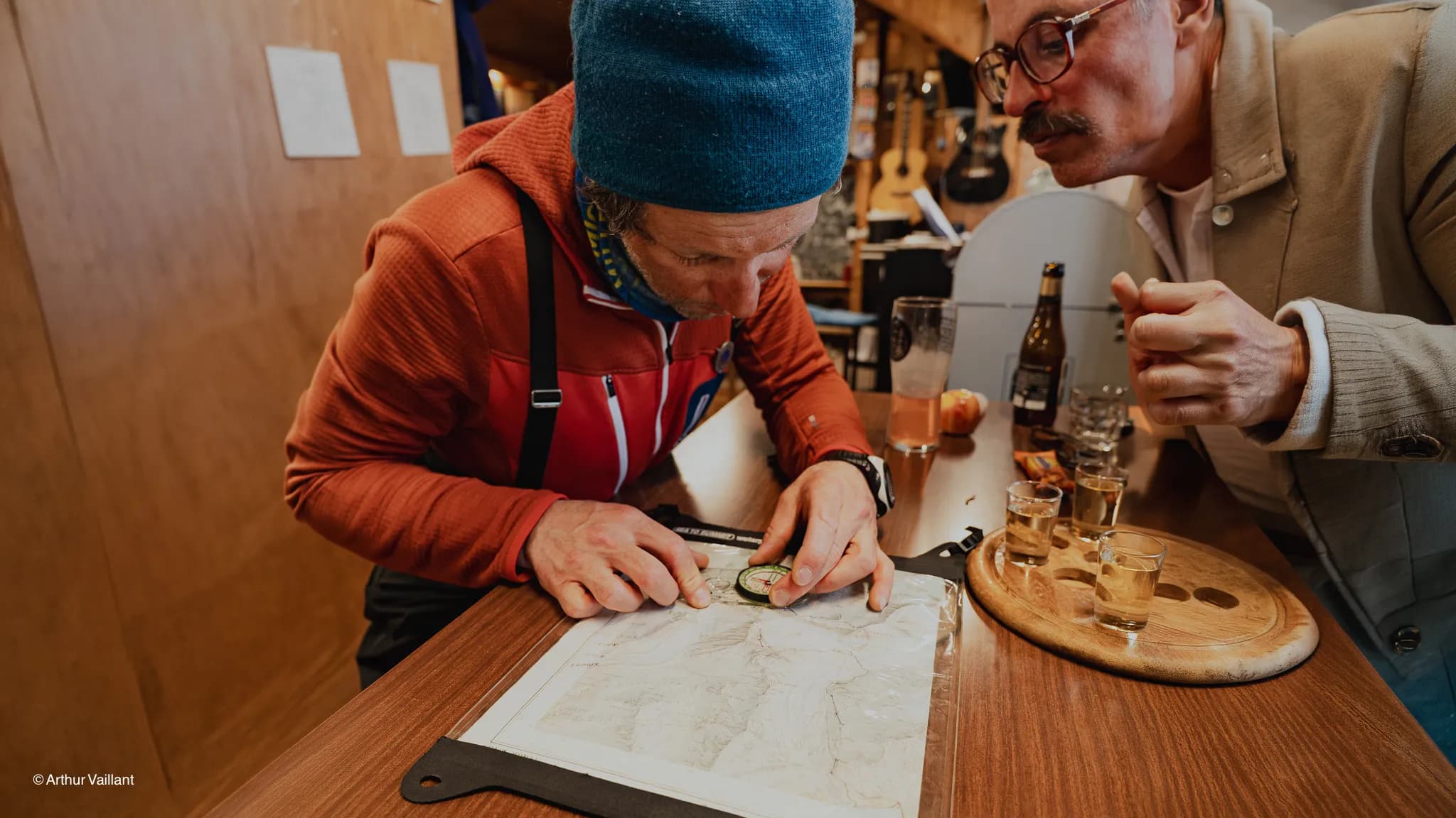 Two men are studying a map, preparing for their adventure-filled expedition to the Alps.