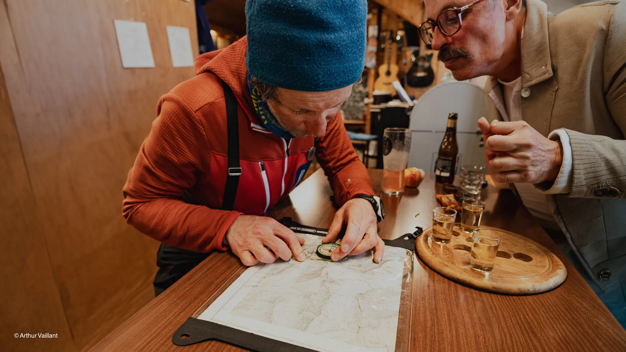 Two men are studying a map, preparing for their adventure-filled expedition to the Alps.