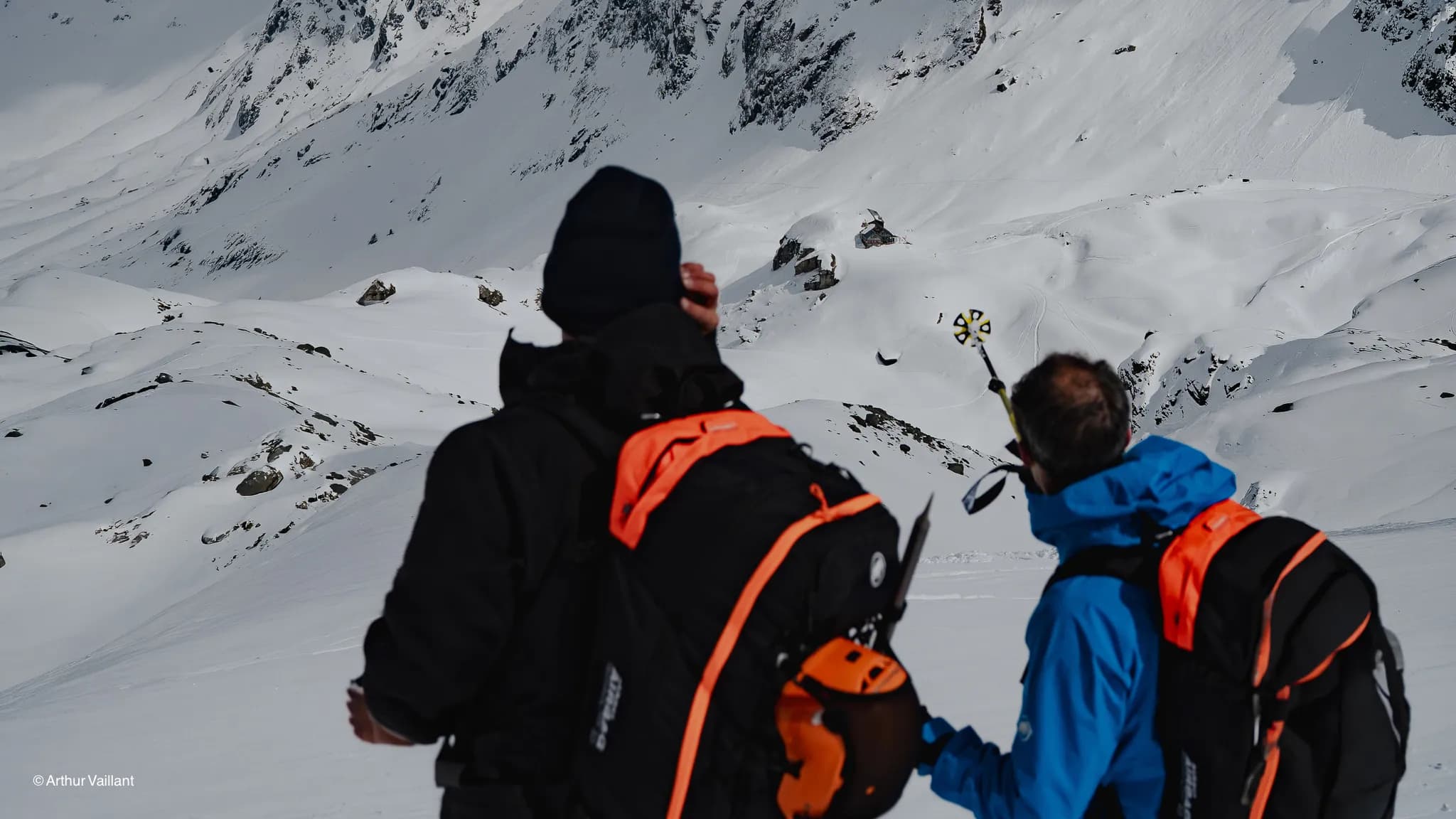 Two skiers are admiring the majestic snow-capped peaks, ready to embark on an alpine adventure.