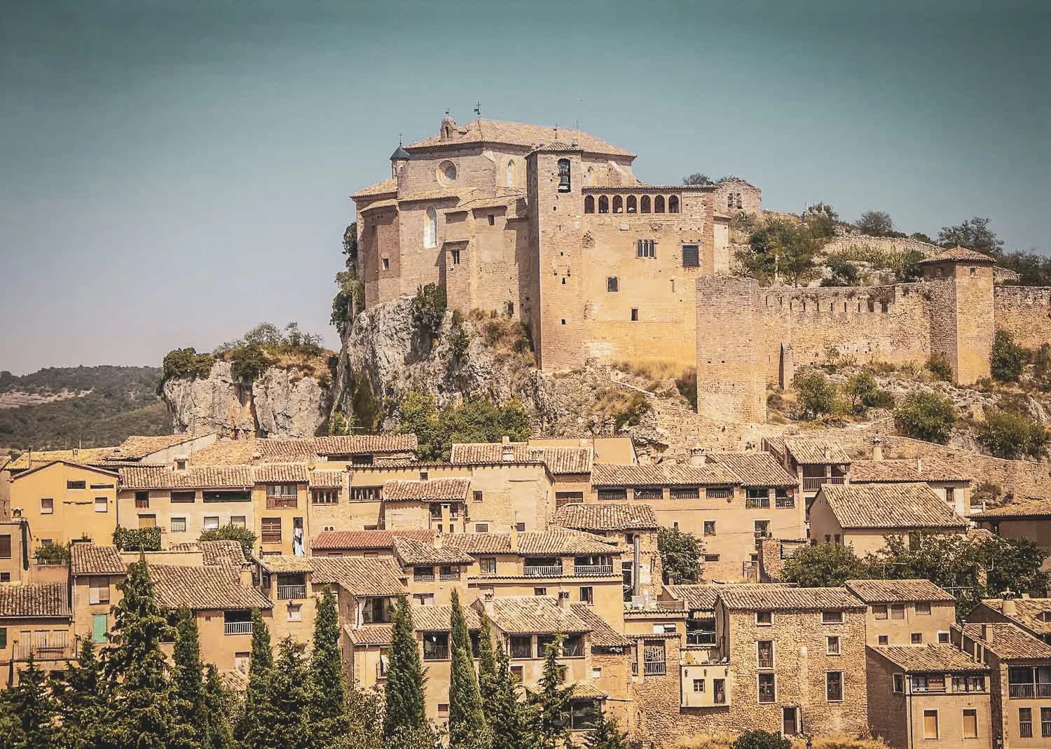 Picturesque castle overlooking a village with tiled roofs, idyllic setting in the Sierra de Guara.
