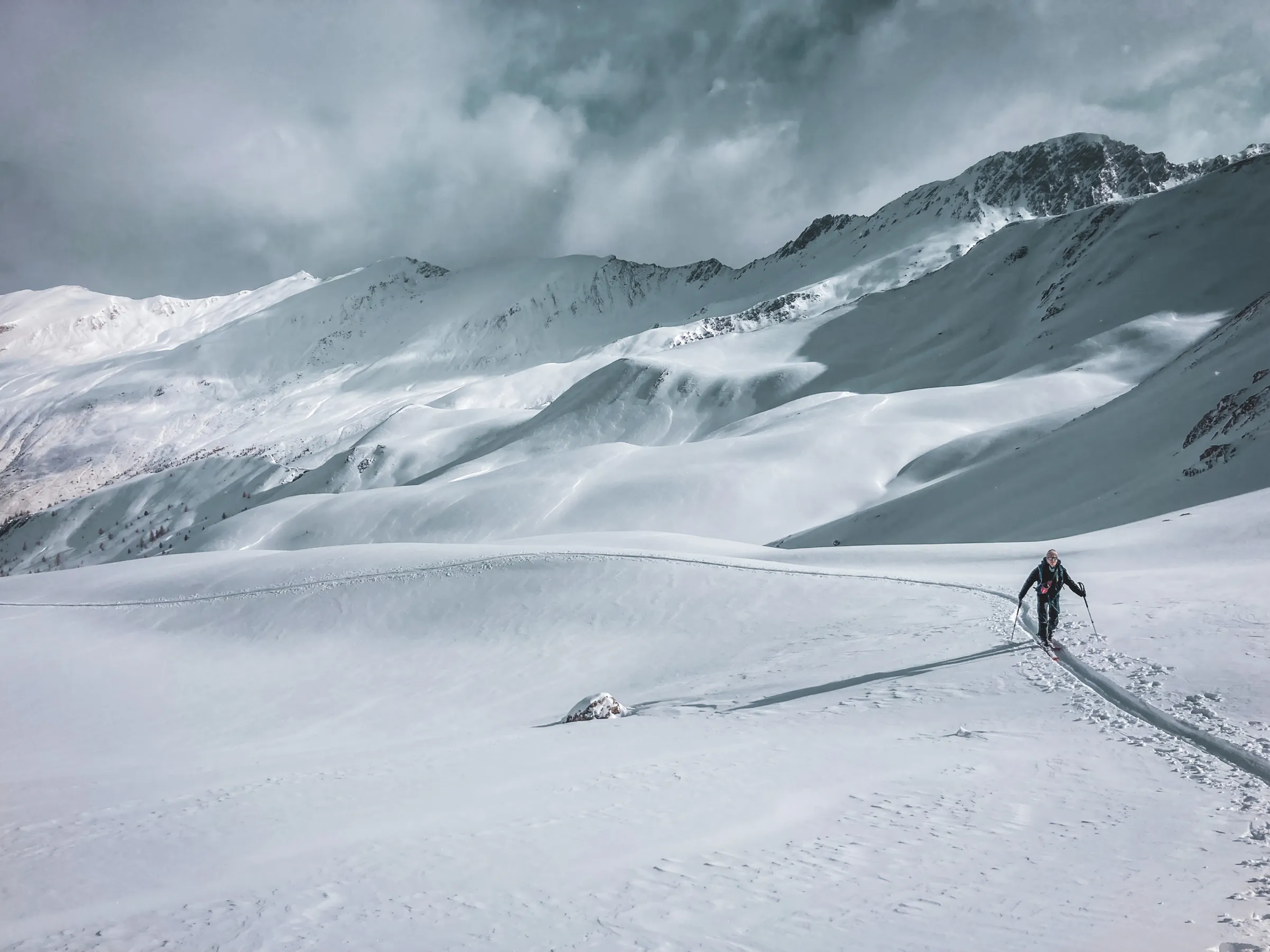 A lone skier wanders through majestic snow-covered landscapes in the heart of the Queyras peaks.