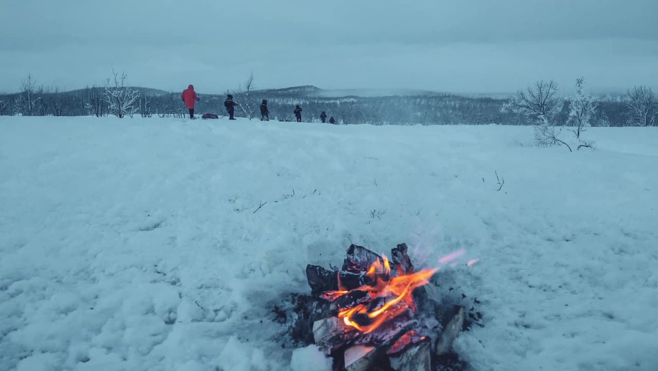 A comforting soak in a snowy landscape, with adventurers on snowshoes on the horizon.