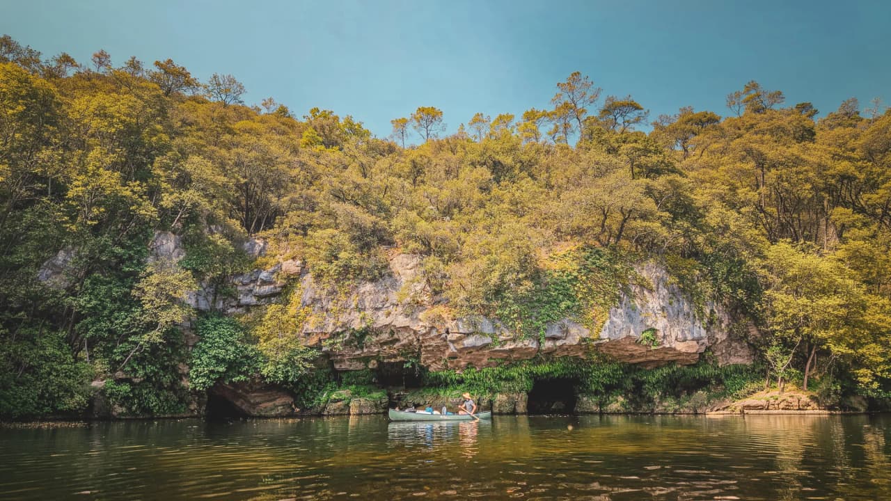 Canoë sur la Dordogne, entouré de verdure et de falaises, invitation à l'aventure en pleine nature.