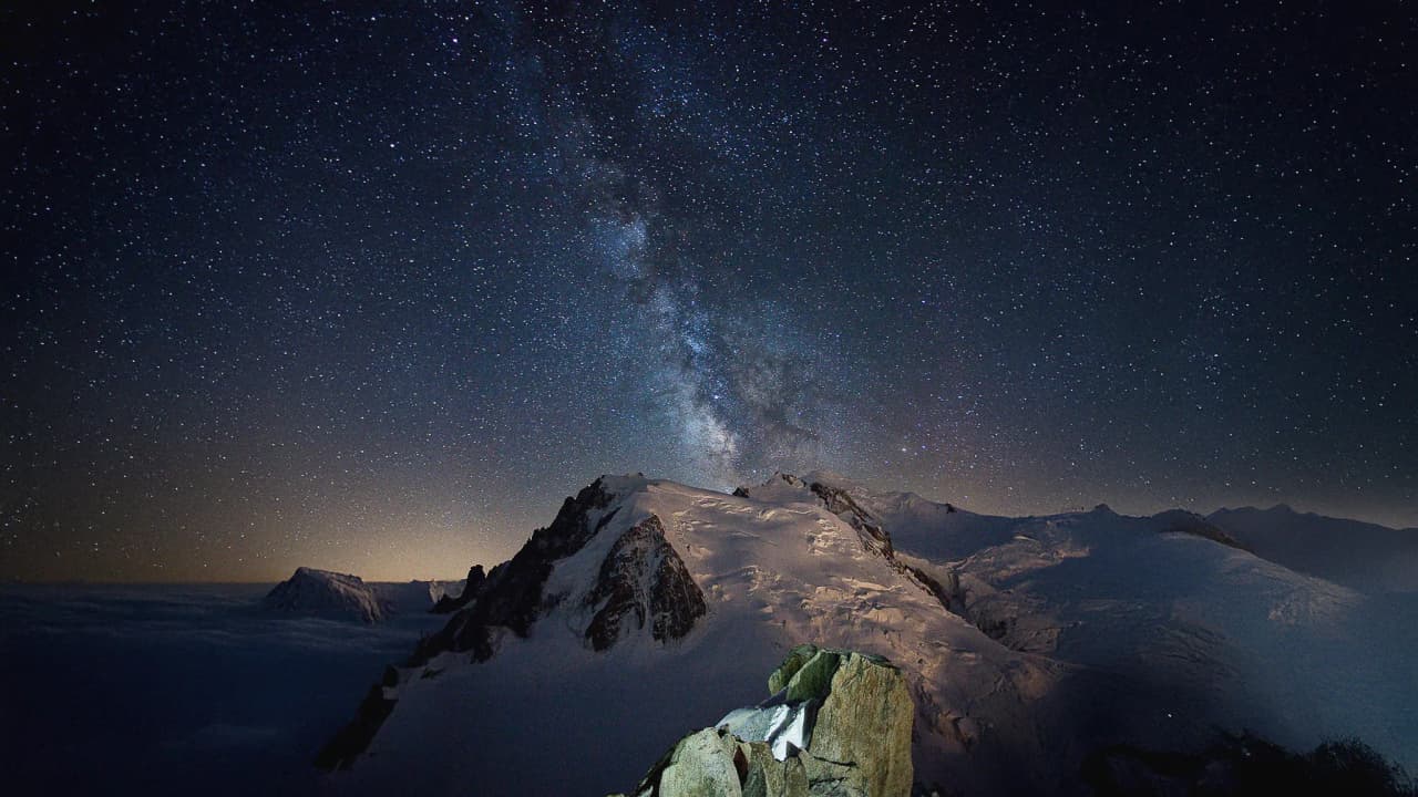 Sterrenhemels boven de besneeuwde toppen van de Mont Blanc, een uitnodiging voor avontuur in het hooggebergte.