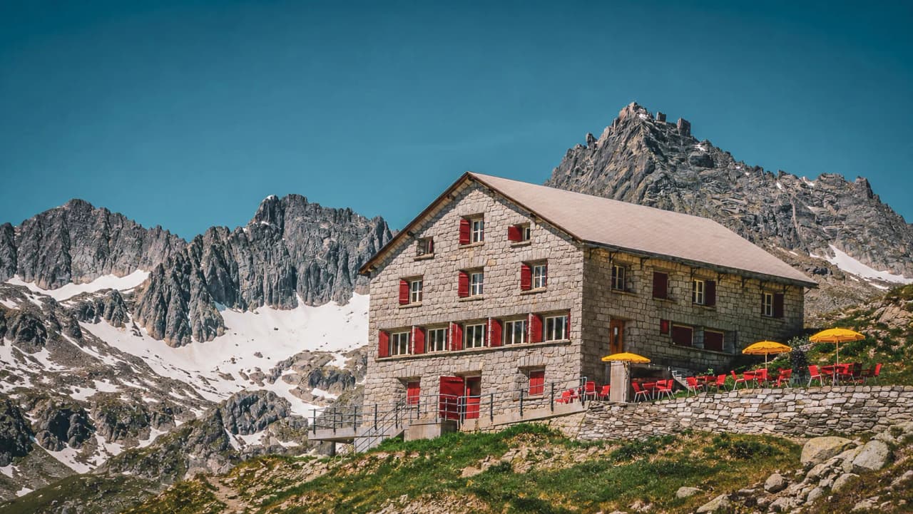 Refuge alpin en pierre, entouré de sommets majestueux, invitant à l'aventure.